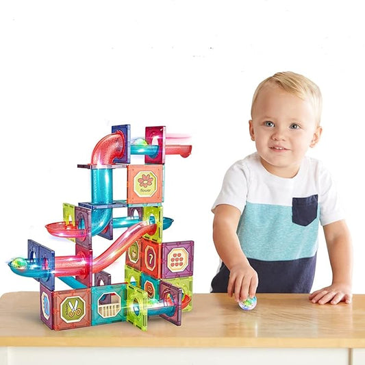 Child playing with a colorful marble run toy on a wooden table.