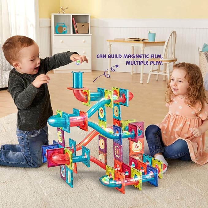 Two children playing with a colorful marble run toy in a room.